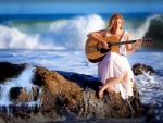 girl strumming guitar in a sea cliff