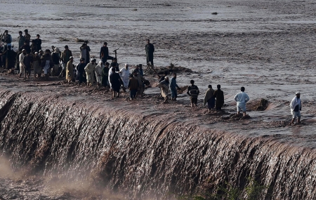 Pakistani residents cross a flooded street - Landslides, Peshawar, 53 killed, Pakistan, Kashmir, Collapsed roofs, 60 injured, Heavy rain