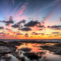 Cloudy Sun Setting over Rocky Sea