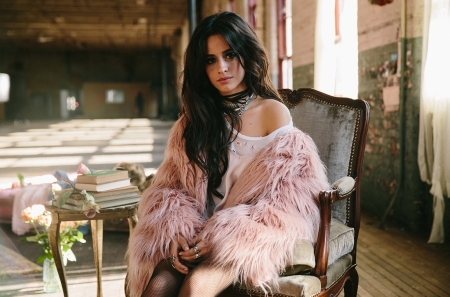 Camila Cabello - pink top with feathered sleeves, flowers, rings, table, brunette, sitting, necklaces, chair