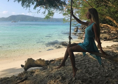 Anjelica Ebbie in a Far Away Place - trees, blue sheer dress, bare feet, beach, sitting on pole swing, blonde, sand, seashore