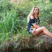 Blonde girl sitting in the meadow