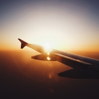 An airplane wing backdropped by a sunset sky