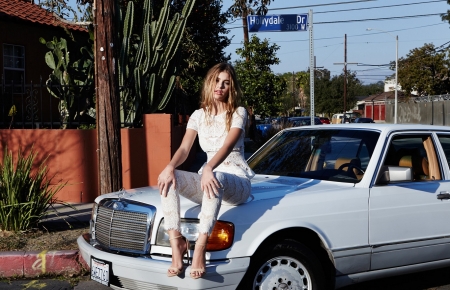 Camilla Marrone - dark blonde, high heels, combo ring bracelet, white lace top, lace pants, sitting on a white mercedes