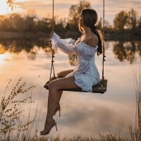 Brunette straddling the swing at sunrise