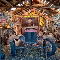 Old vehicle in a garage filled with signs from around the Eastern Sierra, Bishop, CA