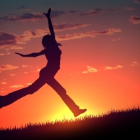 Vector of a female silhouette jumping for joy in a field at sunset