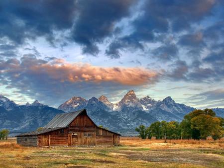 over a clody sky - dark sky, fields sunset, mountains, barn