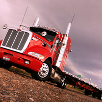 A Peterbilt 386 In Tow With A Spread Axle Flatbed Trailer
