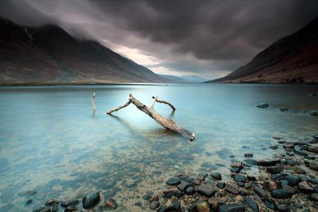 Solitude - clouds, sea, stormy, driftwood, mountains, rocks, sky