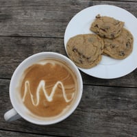 A CUP OF COFFEE WITH A COUPLE OF COOKIES