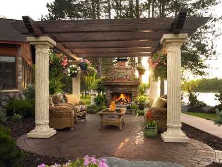 Beautiful backyard - window, chairs, flowerpots, flowers, fireplace, columns, fire, plants, lake, yard, house, sunlight, trees, sofas, pillars, hearth, patio