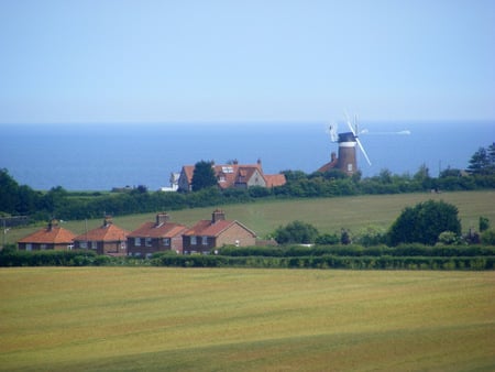 Windmill in the distance. - hedges, fields, sea, houses, windmill, sky