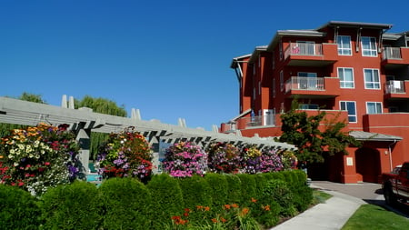 A Colorful morning - summer, red, resort, hanging baskets, flowers, blue sky, lake, sky, morning, building, colors, colorful