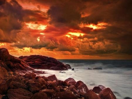 A Fiery Storm - clouds, water, photography, light, orange, shore, red, sun, sky, rocks