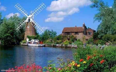 Windmill and House By The River - trees, clouds, river, windmill, blue sky, house, flowers