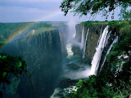 Victoria Falls with a Rainbow - zimbabwe, zambezi river, victoria, water, waterfall, hot, sky, sunny, rainbow, africa, waterfalls, scene, trees, nature, victoria falls