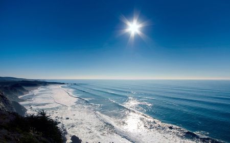 Glistening Sea - horizon, sunny, water, foam, blue, beach, ocean, sand, froth, white, surf, cliffs, waves, sun