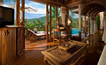 Tropical retreat - arches, wood, sunchair, lounges, mountain, villa, umbrella, mirror, palm trees, towels, coffee table, checkers, curtains, windows, table, chair, pool, wooden floors, flatscreen, retreat