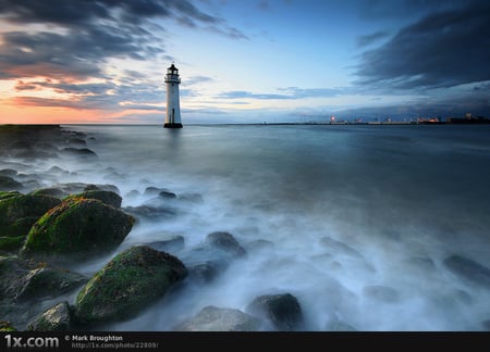 Distant lighthouse - lighthouse, blue, sea, sunrise, harbour, ocean, sunset, nature, cloud, sky, rocks