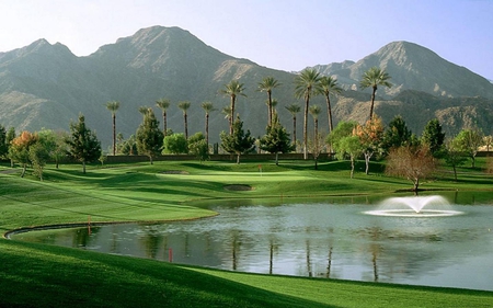 In the Distance - trees, water, fountain, blue, grass, course, mountain, green, day, golf, sky