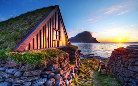 Beautiful Place - beautiful, iceland, ocean, grass, view, roof, nature, sunset, colorful, mountains, rays, landscape, beauty, stones, peaceful, sky, turf, houses, sunlight, clouds, lovely, splendor, house, sea, colors, sunrise, green