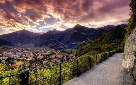 Lovely View - alley, summer, town, splendor, landscape, grass, path, view, bench, houses, sky, clouds, house, trees, beautiful, road, beauty, colors, lovely, architecture, fence, buildings, tree, colorful, nature, sunset, green, mountains, peaceful, building