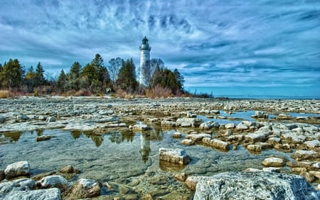 Lighthouse Under Blue - lake, lighthouse, sky, trees, water, scencery, nature, view, blue, clouds, stones