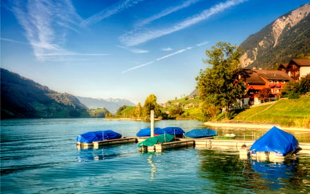 Peaceful Place - beauty, sky, trees, peaceful, water, mountains, view, clouds, architecture, green, sunny, house, tree, grass, boat, houses, lake, boats, landscape, lovely, nature, village, pier, town, beautiful, leaves, splendor, colors