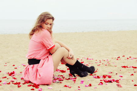 Could it be? - dreamer, beach, rose petals, sand, dreamer girl, red, face, dreaming, water, sea, beauty, colors, love, lovely girl, petals, hair, beautiful lady, thinking, pink dress