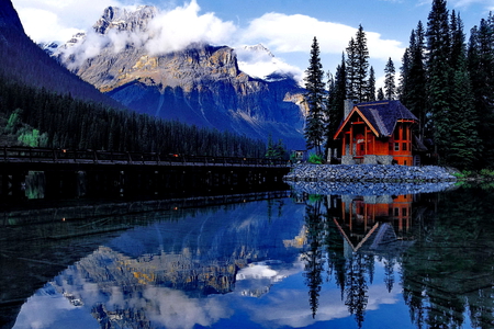 House on the shore of the mirrored lake - lakeshore, cottage, sky, trees, riverbank, peaceful, water, mirrored, calm, reflection, calmness, river, clouds, house, snowy, lake, mountain, summer, shore, peaks, nature, snow, beautiful, cabin