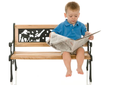 Cute boy setting on bench reading newspaper - newspaper, boy, shorts, bench, reading